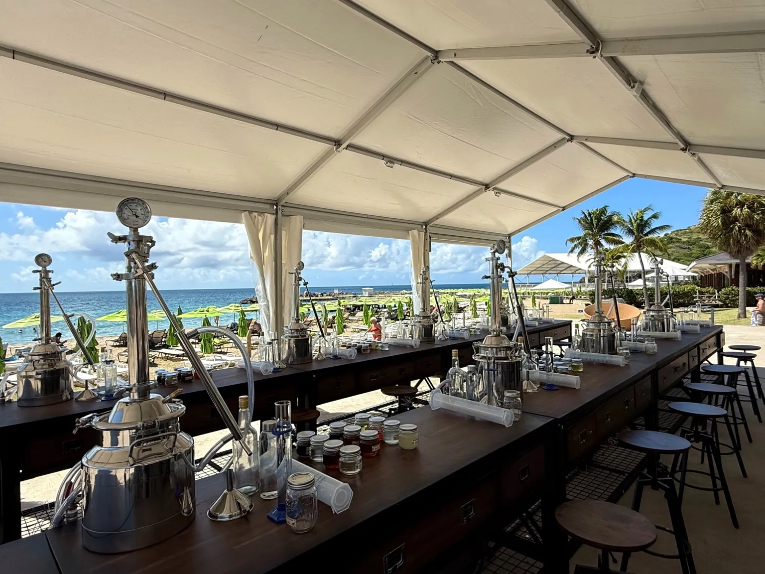 Rum-making stations with stills and ingredients in an open-air seaside classroom.