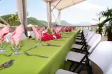 A long table with green linen, flowers and place settings on Carambola’s seaside terrace.