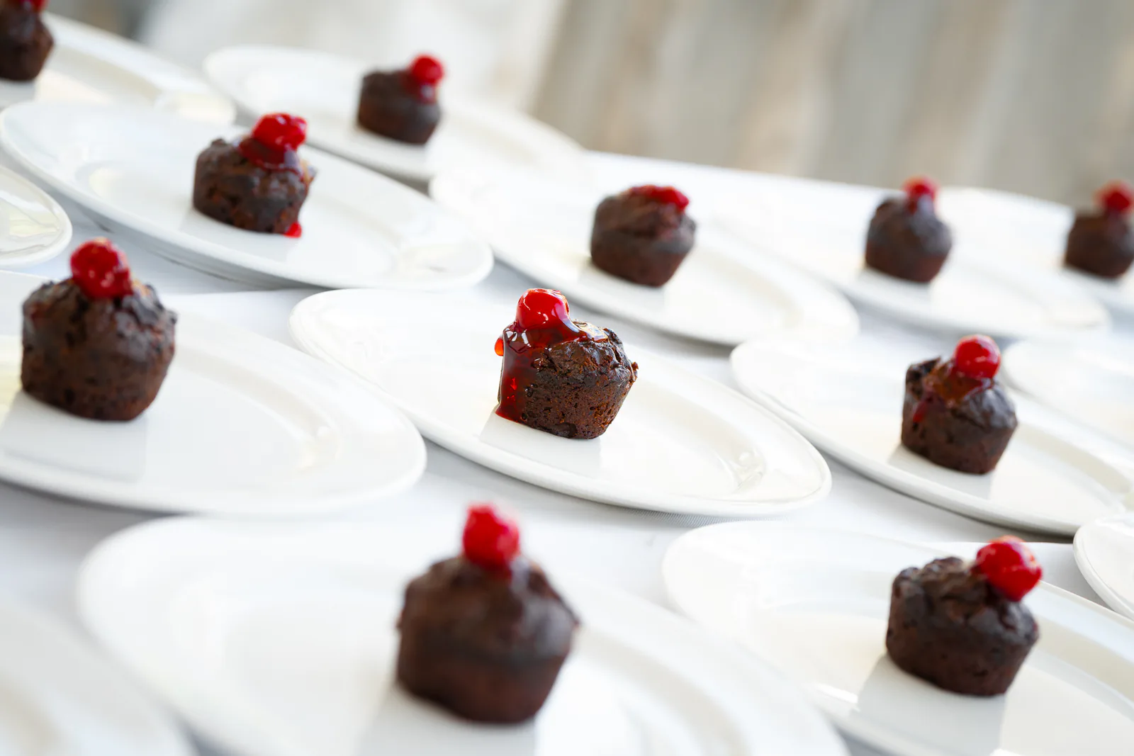 Individual dark cakes topped with red garnishes on white plates at Carambola.