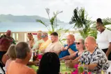 Foodie tour guests and a host gather around a table overlooking the sea at Carambola.