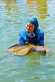 A guest in blue snorkeling gear beside a stingray in the lagoon.